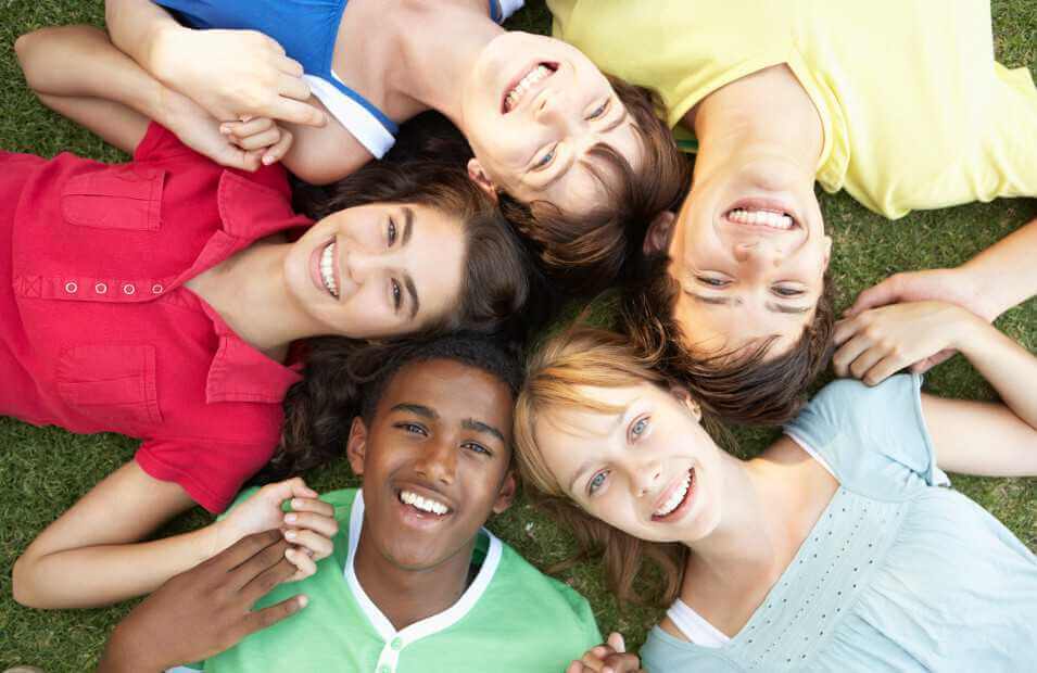 group of kids smiling while laying in the grass