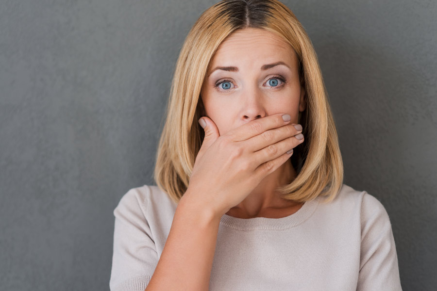 woman with halitosis covering mouth