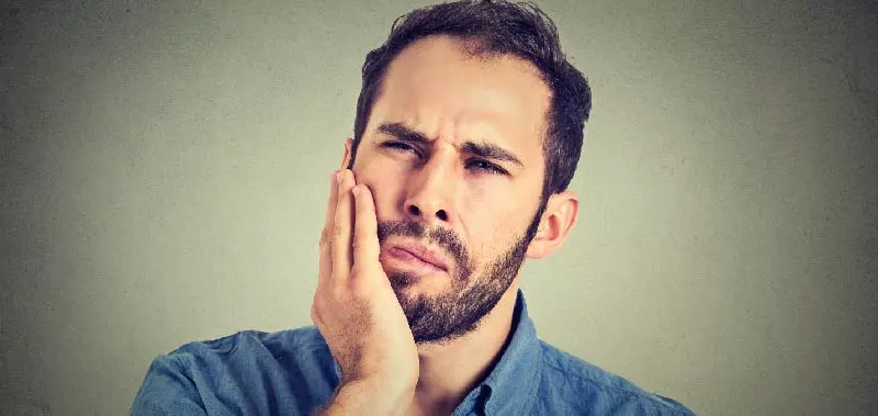 man experiencing tooth pain after his dental crown fell out