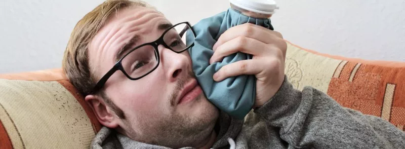 man icing his mouth due to wisdom tooth pain